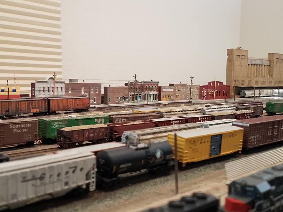 RAILRAOD AVENUE ON MY N SCALE LAYOUT A VIEW ACROSS THE BUSY RAIL YARD ON MY N SCALE MODEL RAILROAD. IN THE BACKGROUND IS RAILROAD AVENUE, BUILT AS A LOW RELIEF FLAT COMBINATION TO ADD DEPTH TO THE SCENE.