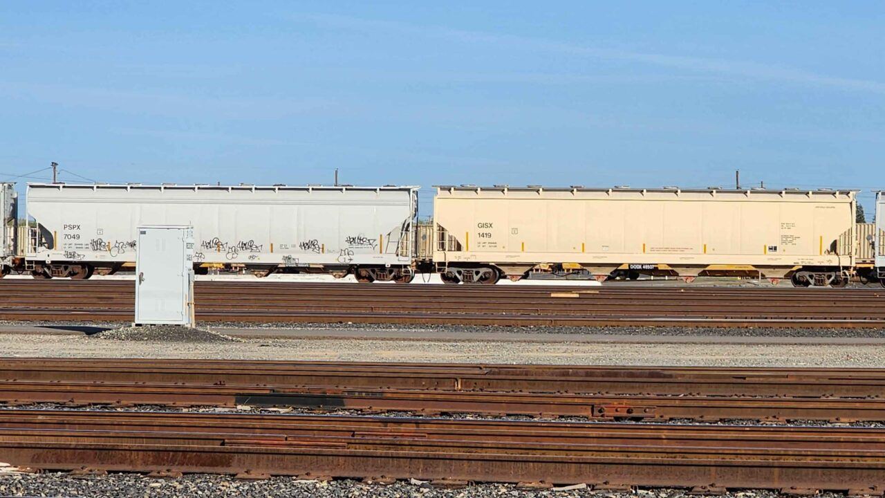A PAIR OF 4 BAY COVERED HOPPERS IN RAILROAD YARD