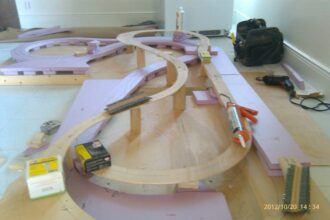THE BEGINNING OF A MODEL TRAIN LAYOUT. HERE YOU SEE THE PLYWOOD BASE AND TRACK BASE CUT FROM PLYWOOD WITH A JIGSAW TO CREATE THE CURVES