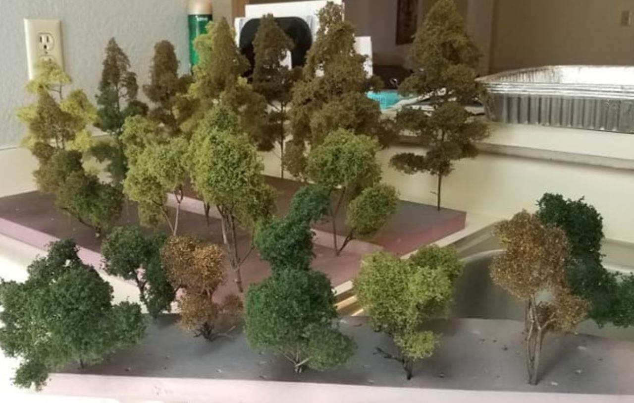 A PHOTO OF VARIOUS TYPES OF HOME MADE TREES FOR MY MODEL RAILROAD USING NATURAL MATERIALS FOUND OUTDOORS, SOME PILLOW FIBERS TO REPRESENT FINE BRANCHES, AND VARIOUS SHADES OF GROUND UP FOAM RUBBER TO SIMULATE THE LEAVES.